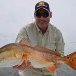 Man in white outfit with the redfish he caught