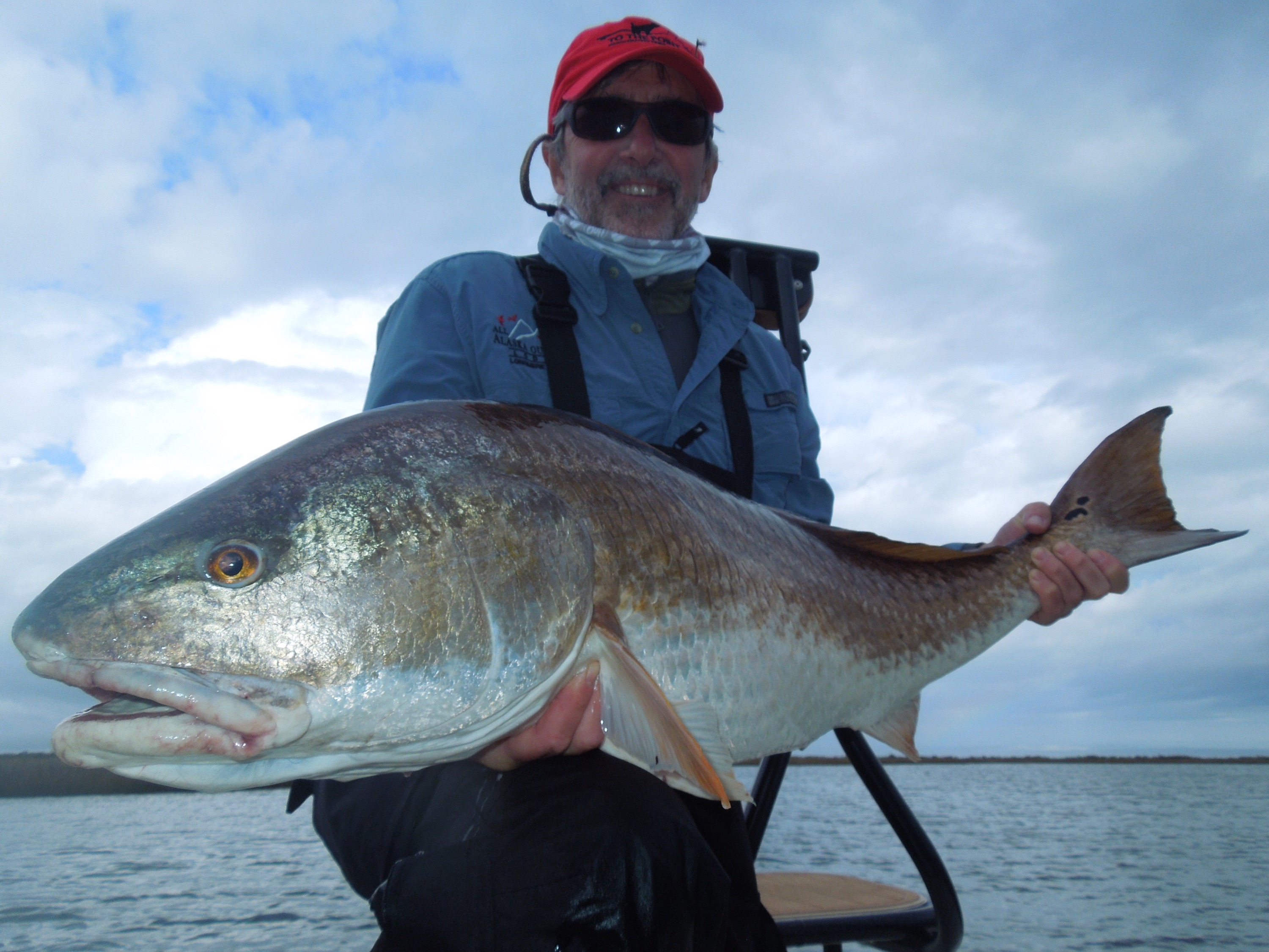 Man smiles with the huge redfish he captured
