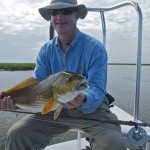 Old man in blue shirt smiles with his catch