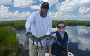 Man holds a baby alligator while posing with his son