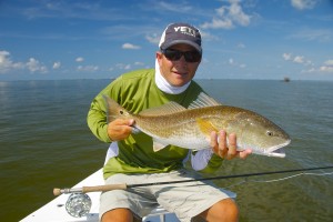 Man in green T shirt posing with the fish he caught