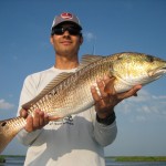 Man in grey cap holding the fish he just caught