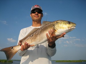 Man in grey cap holding the fish he just caught