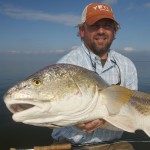 Man in orange cap holding the fish he just caught