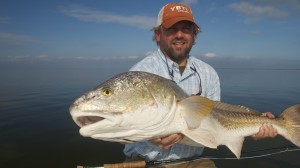 Man in orange cap holding the fish he just caught