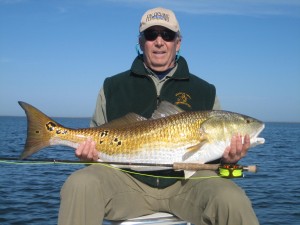 Man in dark jacket posing with the fish he caught