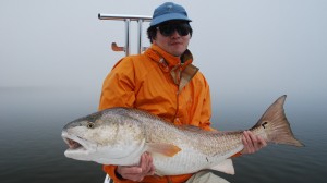 Man in orange fishing suit displays his catch