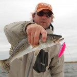 Man in orange cap holds on to a freshly caught fish