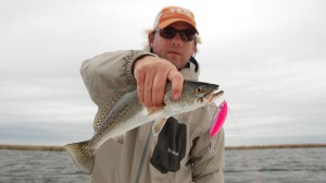 Man in orange cap holds on to a freshly caught fish