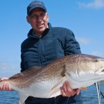 Man in blue cap shows his catch to the camera