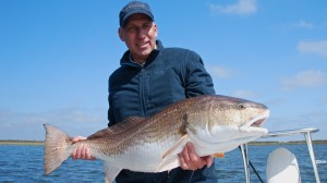 Man in blue cap shows his catch to the camera