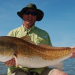 Man in green shirt poses with his catch