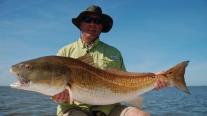 Man in green shirt poses with his catch