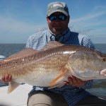 Man in blue check shirt poses with his catch