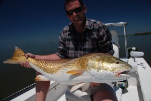 Man in check shirt poses with the fish he caught