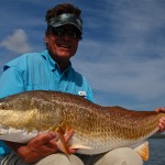 Man in sky blue shirt poses with the fish he caught