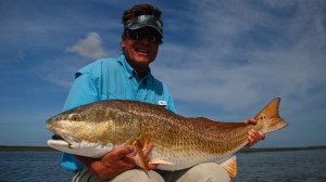 Man in sky blue shirt poses with the fish he caught