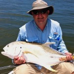 Man in hat smiles holding a large fish he caught