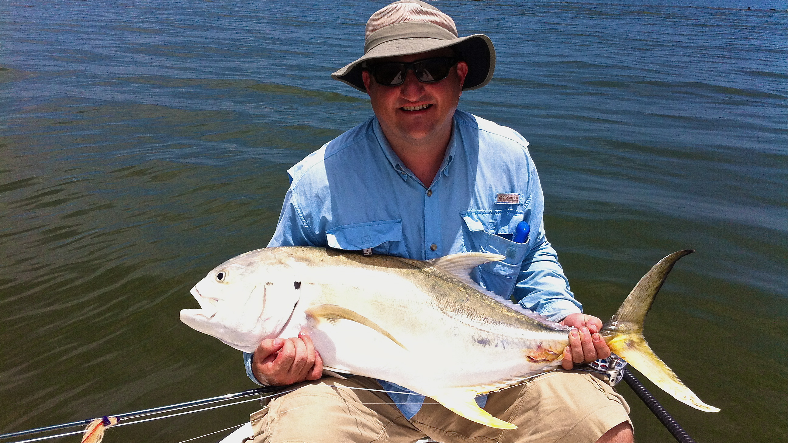 Man in hat smiles holding a large fish he caught