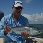 Man in light blue shirt poses with the fish he caught