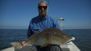 Man in blue shirt posing with the fish he caught