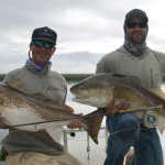 Two men strike a pose with the fish they caught