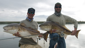 Two men strike a pose with the fish they caught