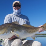 Man in light blue outfit shows the fish he just caught