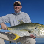 Man in light blue outfit posing with the fish he just caught