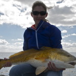 Woman in dark blue outfit shows the fish she just caught