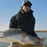 Man in dark jacket shows the fish he just caught