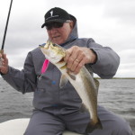 Man in grey overalls shows the fish he caught