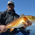 Man in dark outfit with the redfish he caught