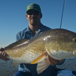 Man in blue color outfit poses with the fish he caught