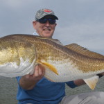 Middle aged man smiles after catching a fish