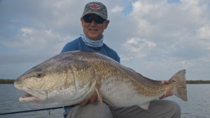 Man in blue dress smiles with his catch