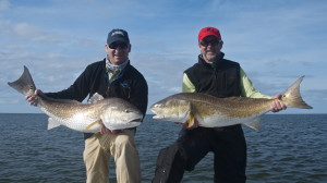 Two men strike a dynamic pose with their fishes