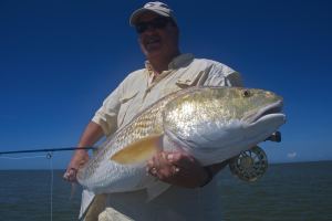 Man in white shirt shows the fish he caught