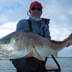 Man smiles with the huge redfish he captured