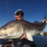 Man smiles with a huge fish captured during a trip