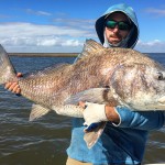 Man displays a huge fish captured during a trip