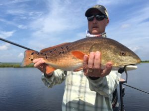 Man posing with a freshly caught redfish