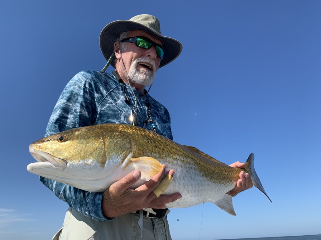 An old man enjoys posing with the fish he caught